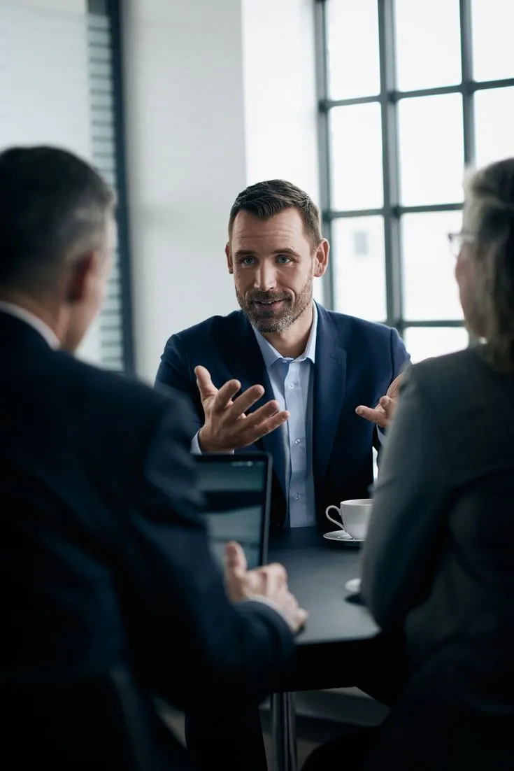 An adviser in conversation with two clients across a meeting table